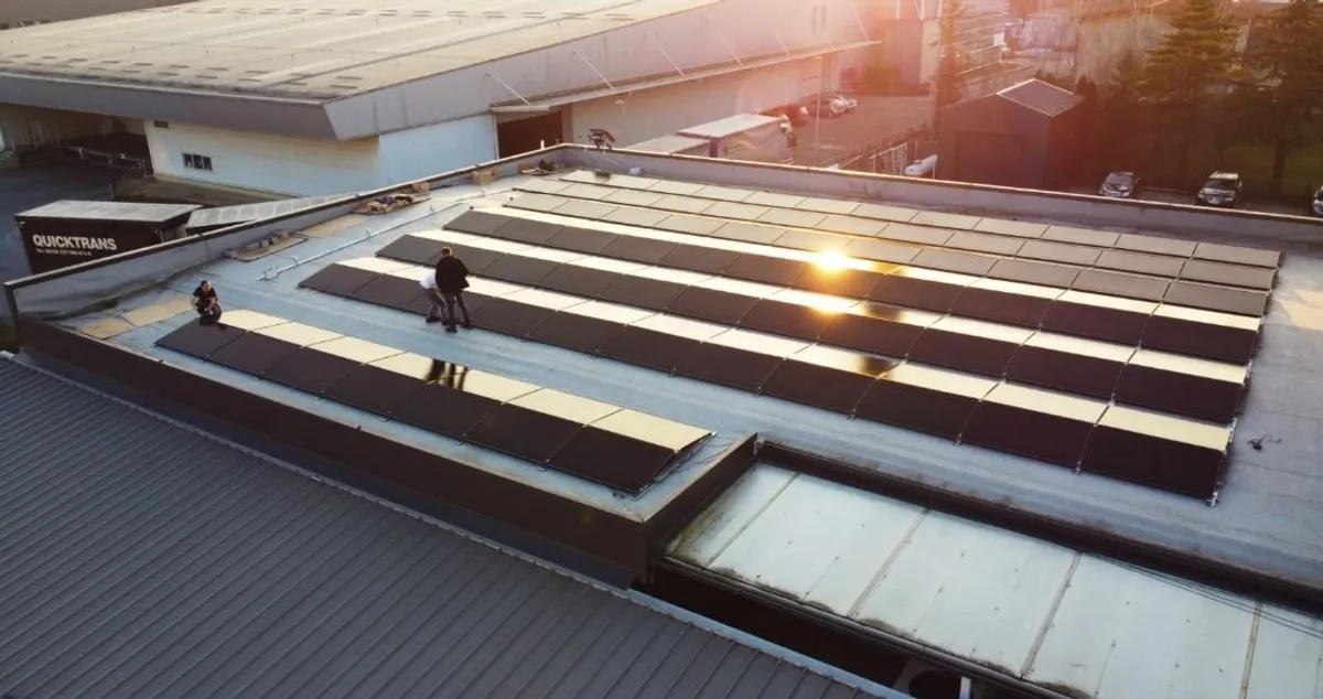 Veliki krovni sustav na ravnom krovu industrijskog objekta, snimljen tijekom završne montaže pri zalasku sunca.